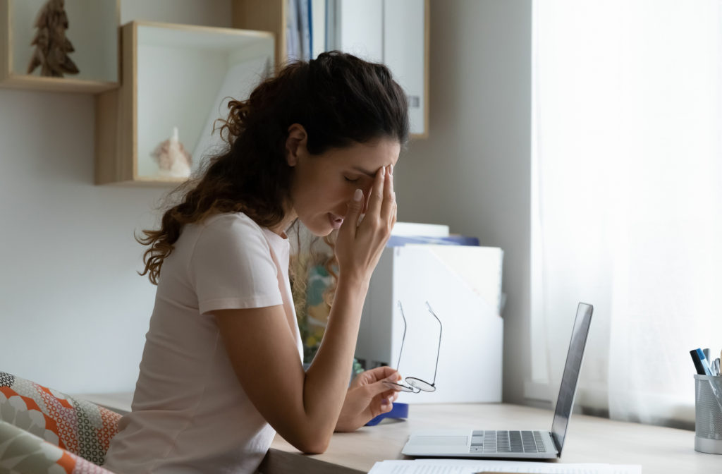 Young woman touching eye while using laptop