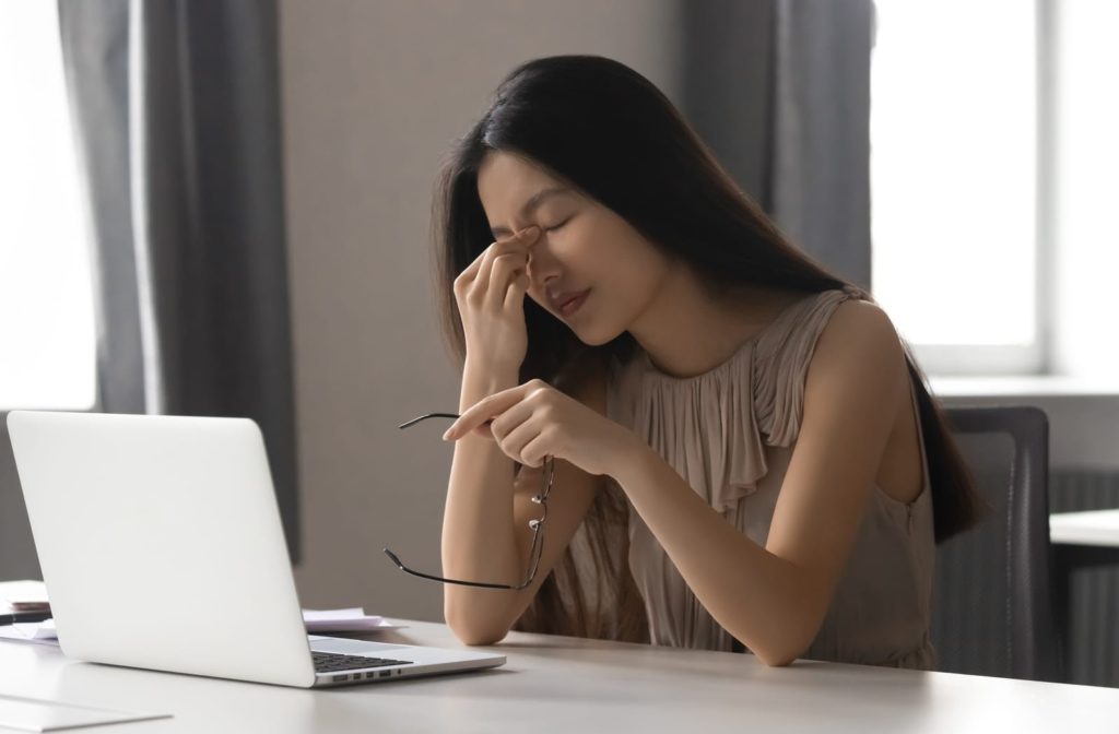 Young women experiencing digital eye strain while using her laptop