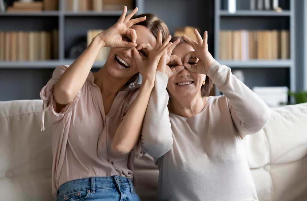 Daughter and mother making binoculars gesture to show healthy vision and eyes