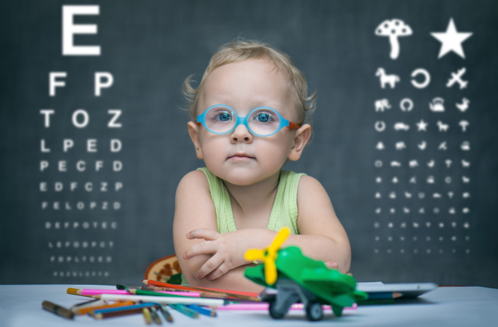 Young girl undergoing eye exam at optometrist office with eye exam chart in the background