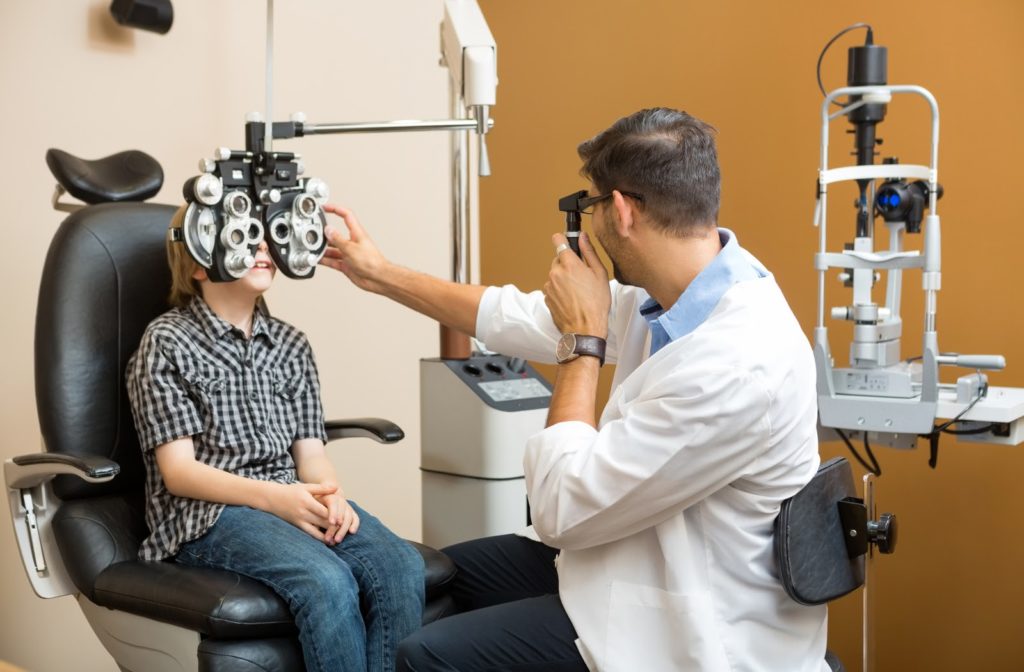 Young boy undergoing eye exam from eye doctor at optometrist office