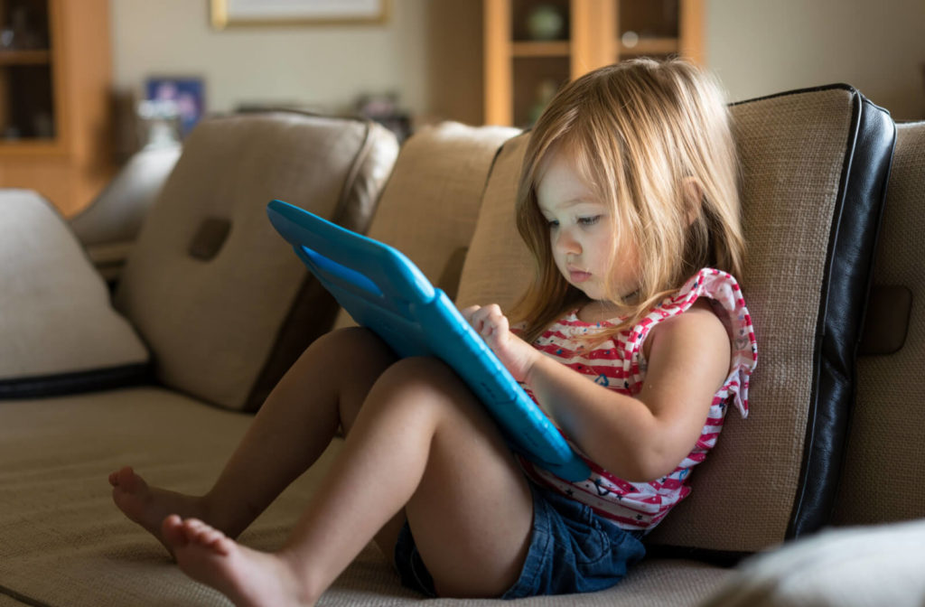 Young girl using a tablet while sitting on a couch