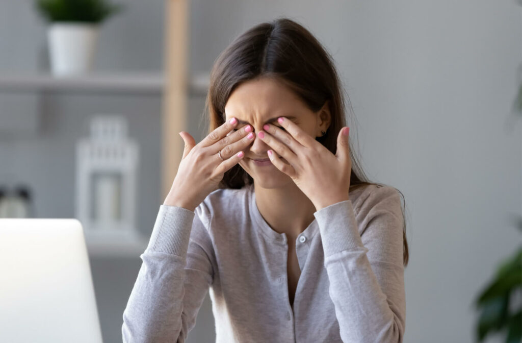 A young lady sitting in front of her computer is scratching her irritated dry eyes with both her hands. Lipiflow is a treatment for dry eyes. It uses heat and massage to improve the  symptoms.