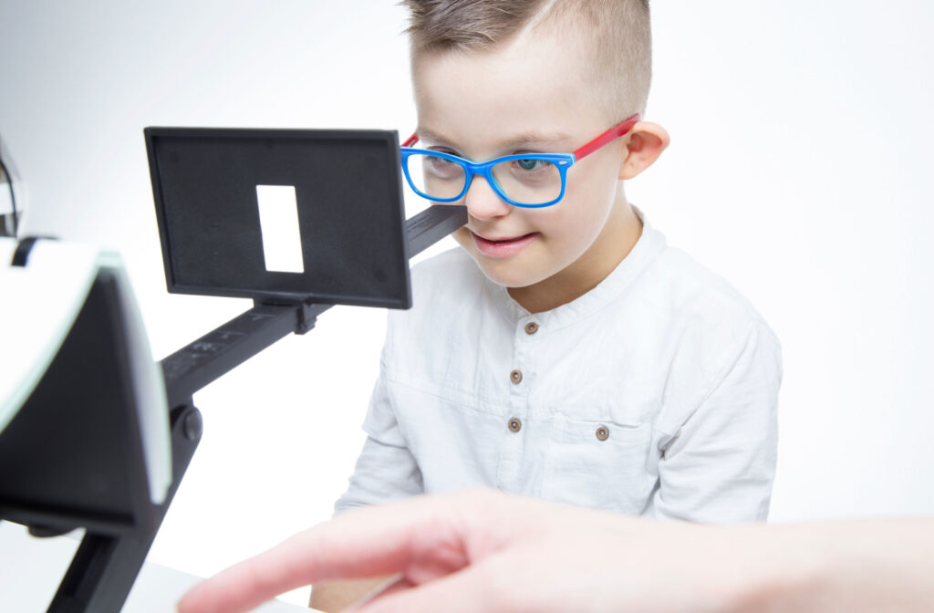 A young boy undergoing vision therapy, looking through an aperture device. The device is used to improve eye coordination and focus, and is often recommended for individuals with certain visual disorders.
