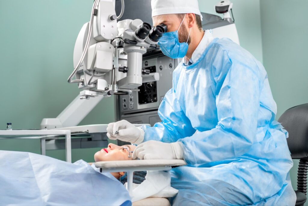 A male surgeon looking through a microscope while performing cataract surgery on a female patient.