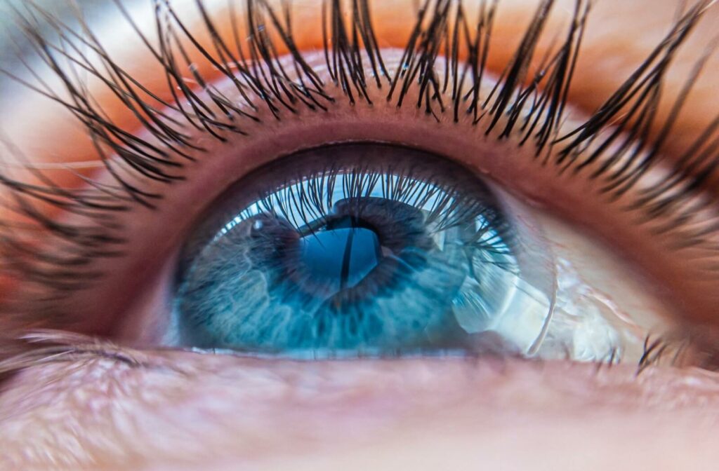 An extreme close-up of a person's eye as they look upward. A contact lens is visible on the surface of their eye.