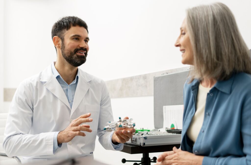 Interested adult speaking to an optometrist holding a vision tool during a comprehensive eye exam.