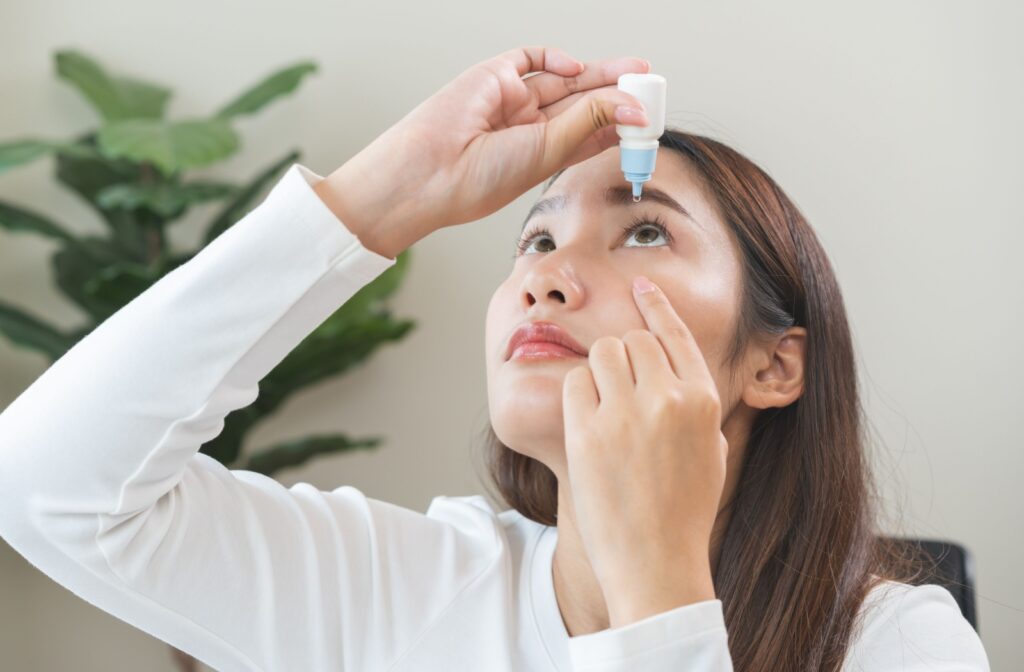 A person gently pulls down their lower eyelid to apply eyedrops.