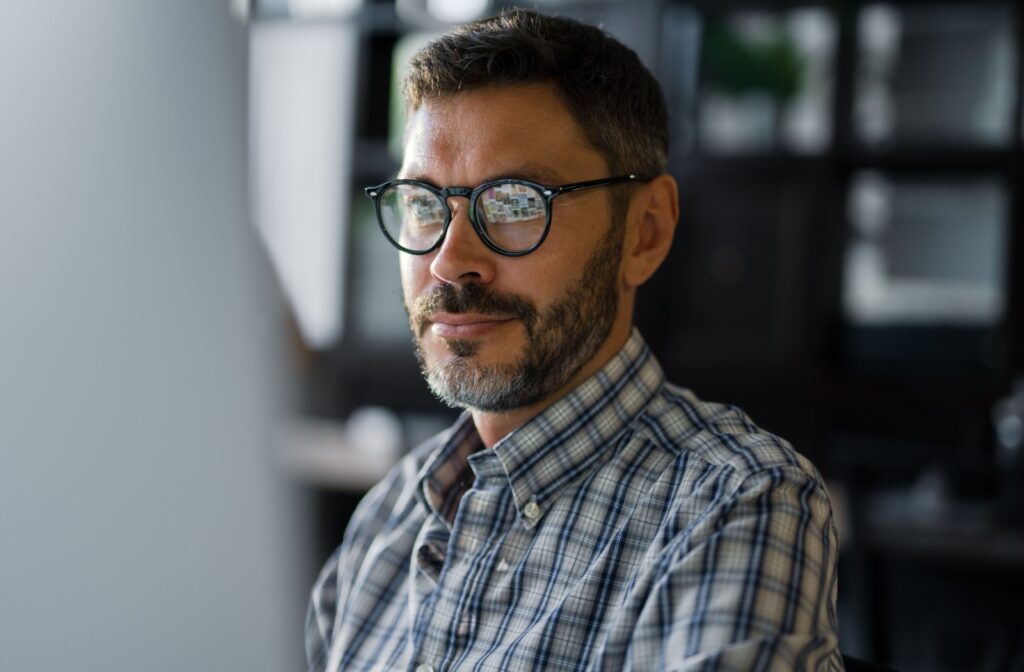 A person with glasses works comfortably on their office computer.