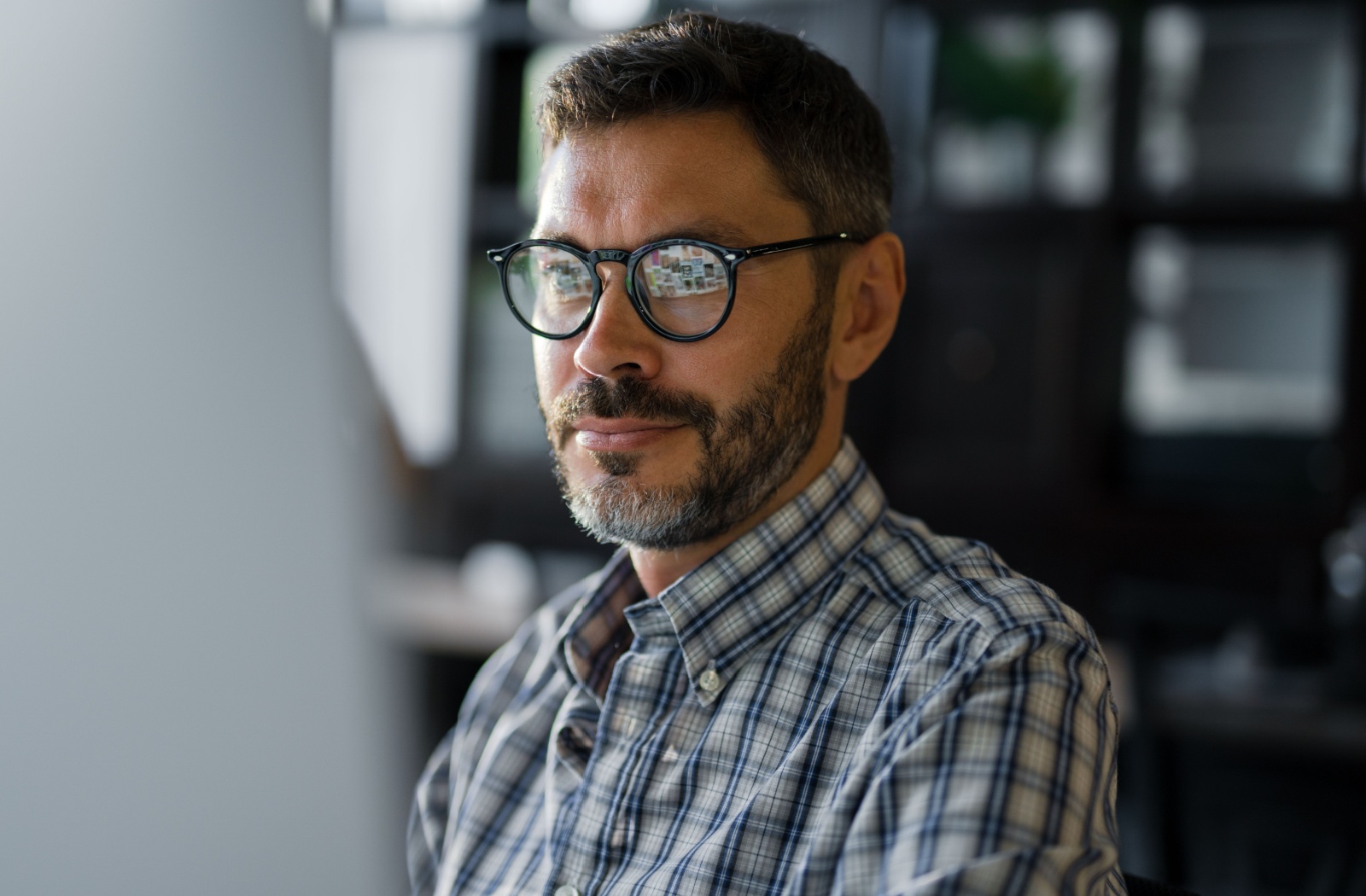 A person with glasses works comfortably on their office computer.