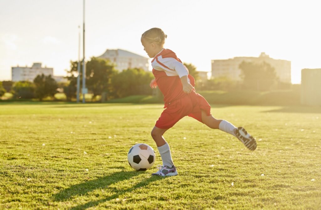 A child playing soccer outside and wearing contact lenses for nearsightedness.